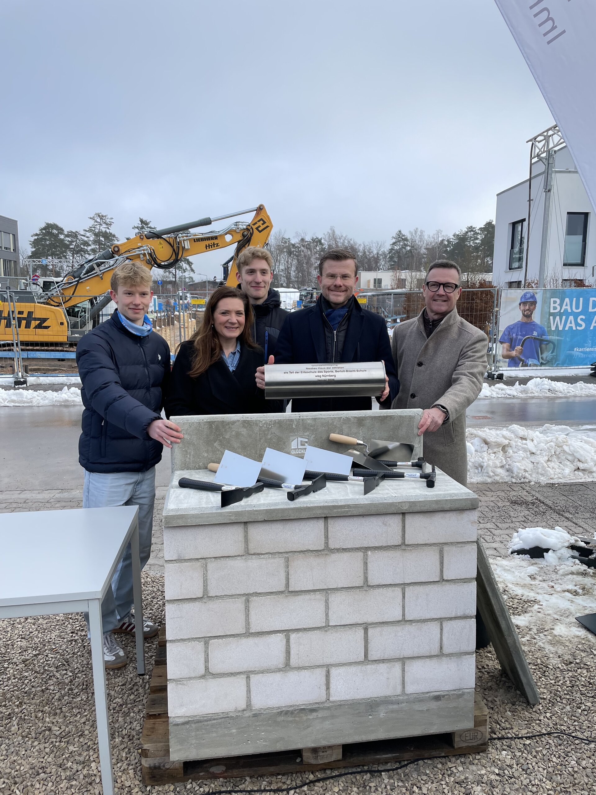 Vier Personen stehen hinter dem symbolischen Grundstein.