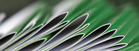 Der Link hinter dem Bild führt zur Seite "Geschäftsberichte". Das Bild zeigt Broschüren, die aufeinander liegen. 