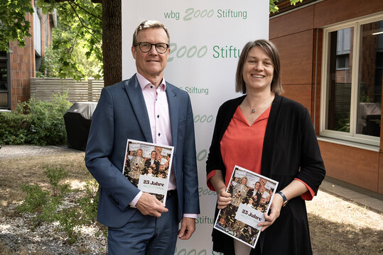 Bildmotiv: wbg-Geschäftsführer und Vorsitzender des Stiftungsvorstandes Ralf Schekira mit Sozialreferentin und der Vorsitzenden des Stiftungsbeirats Elisabeth Ries zeigen die Jubiläumsschrift. Foto: Meike Schulig, wbg Nürnberg