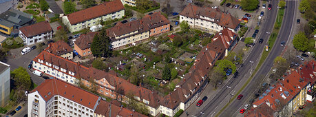Der Link hinter dem Bild führt zur Seite "Quartiersentwicklung". Das Bild zeigt eine Luftaufnahme eines Wohngebietes.